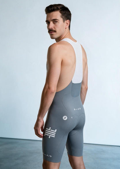 Male cyclist wearing False Flat x Castelli cool grey aerodynamic bib shorts with white mesh suspenders